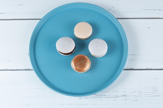 Quattro macarons ripieni di ganache al cioccolato e dulce de leche su una vista dal piatto blu