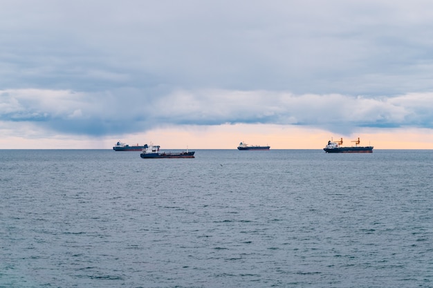 Quattro navi mercantili in acque calme in mare. Cielo nuvoloso