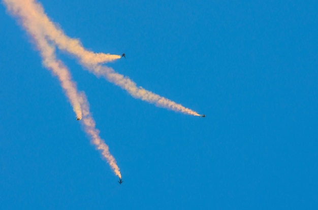 Quattro paracadutisti saltano con il fumo e volano nel cielo blu.