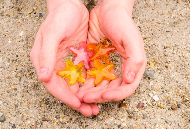 Quattro stelle in mano su uno sfondo di spiaggia di sabbia, il concetto di una vacanza in un hotel a quattro stelle