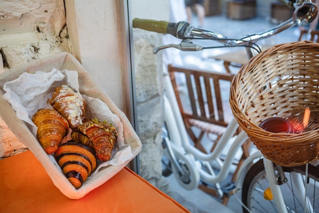 Quattro tipi di croissant in un cestino su un tavolo bianco vicino alla finestra di un bar