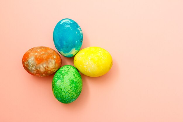 Quattro uova di Pasqua multicolori sulla vista superiore della superficie rosa, spazio per testo. Concetto felice giorno di Pasqua.