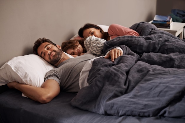 Questa è la felicità Inquadratura di una bambina che dorme accanto ai suoi genitori a letto