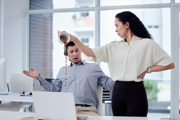 Questa è la vendetta per quello che hai fatto Inquadratura di una donna d'affari che versa una tazza di caffè sulla scrivania di un collega in un call center