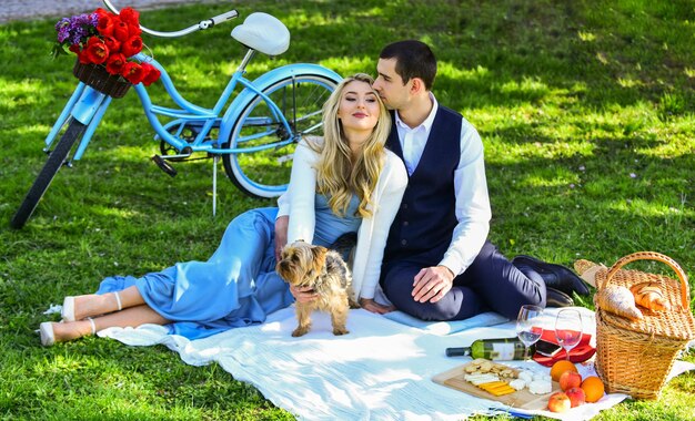 Questo è amore felice coppia innamorata donna e uomo sdraiato nel parco e godersi la giornata insieme San Valentino picnic romantico picnic nel parco con cane coppia carina appuntamento su una bici vintage coperta