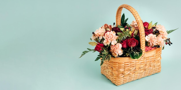 Questo è un bouquet di fiori delicati in un cesto di vimini su uno sfondo blu di colore pastello Banner
