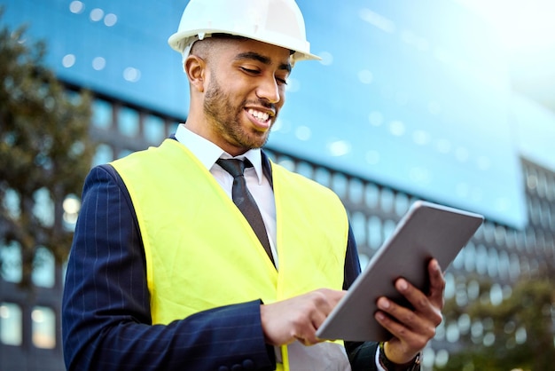 Questo edificio sarà magnifico Inquadratura di un giovane uomo d'affari in un cantiere edile utilizzando una tavoletta digitale