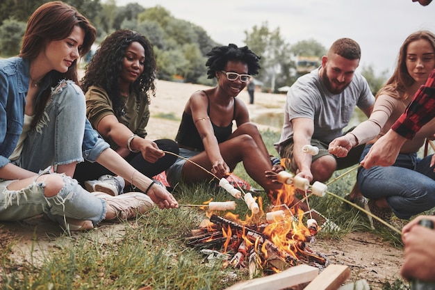 Questo sarà delizioso. Un gruppo di persone fa un picnic sulla spiaggia. Gli amici si divertono durante il fine settimana.