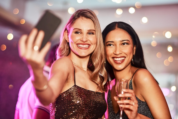 Questo sta andando sui social media Foto ritagliata di due giovani donne allegre che si fanno un autoritratto insieme all'interno di un bar di notte