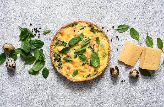 Quiche con salmone e spinaci, formaggio su uno sfondo di cemento chiaro. Vista dall'alto.