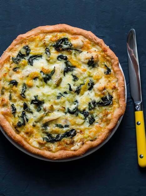 Quiche di spinaci e porri di pollo su sfondo scuro vista dall'alto