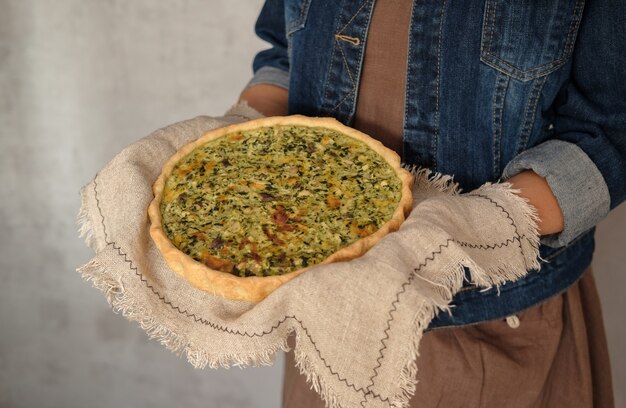 Quiche francese con pollo, funghi e broccoli nelle mani della donna