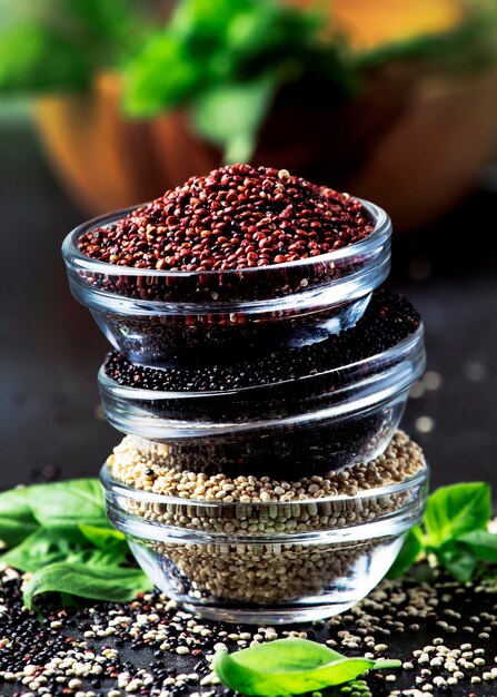 Quinoa bianca e rossa nera in ciotole semole di quinoa cruda tavolo da cucina grigio assortito fuoco selettivo