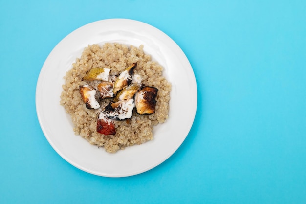 Quinoa cotta con verdure e salsa sul piatto bianco