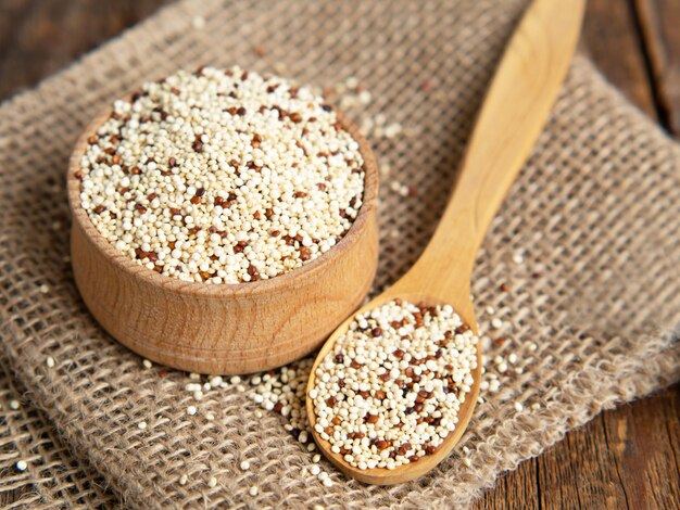 Quinoa cruda mista in ciotole su fondo di legno Cibo sano e senza glutine