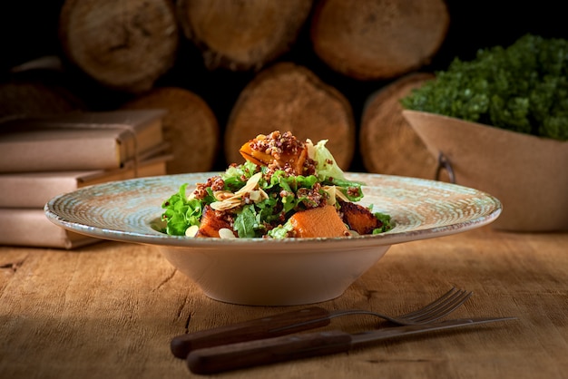 Quinoa e insalata di zucca alla griglia con spinaci freschi su una tavola di legno rustica. Cibo sano e concetto di cibo pulito. Messa a fuoco selettiva