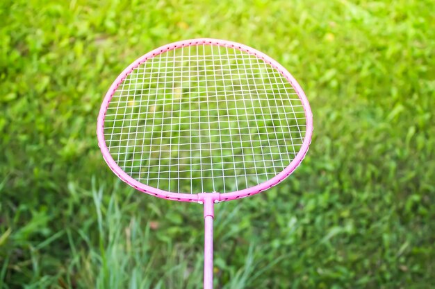 Racchetta da badminton sulla fine verde del fondo dell'erba di estate su.