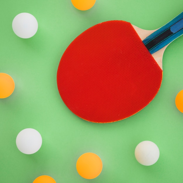 Racchetta da ping pong rosso con palline bianche e arancione su sfondo verde