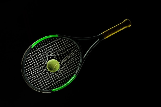 Racchetta da tennis, palla. Attrezzatura sportiva professionale isolata su sfondo nero per studio. Concetto di sport, leadership, competizione, stile di vita sano in movimento e azione, allenamento. Primo piano, copyspace.