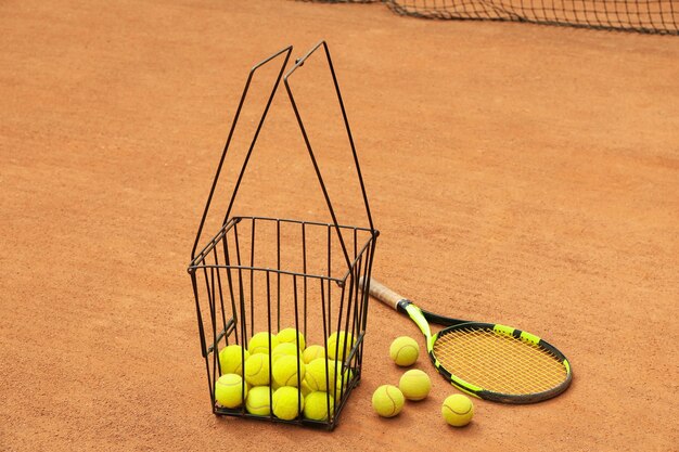 Racchetta e cesto con palline sul campo in terra battuta