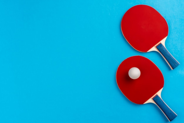 Racchetta e palla di ping-pong su fondo blu