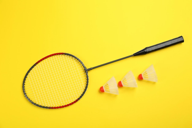 Racchetta e volani su sfondo giallo piatto Attrezzatura da badminton