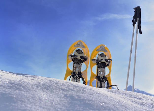 Racchette da neve che piantano nella neve in montagna sotto il cielo blu