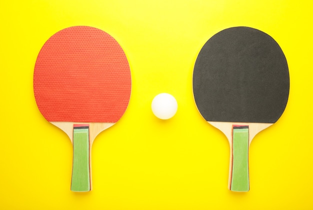 Racchette da ping pong e palline sulla superficie gialla