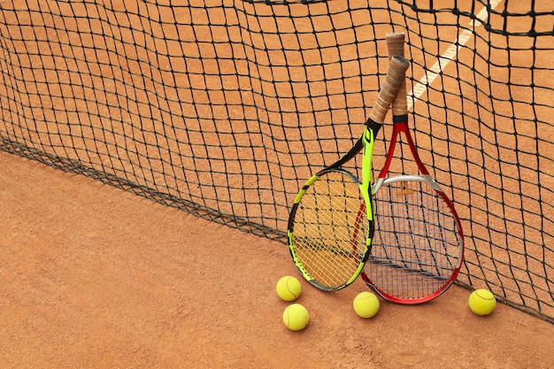 Racchette e palline da tennis contro rete su campo in terra battuta