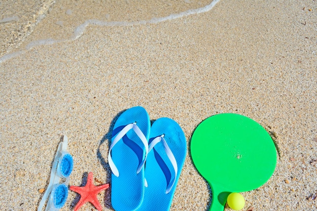 Racchette per sandali e occhiali da mare su una spiaggia dorata