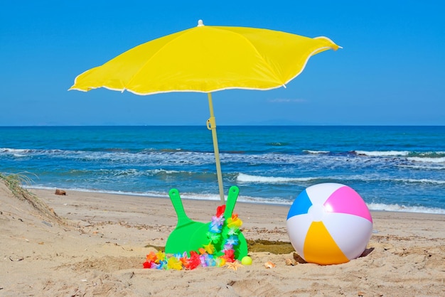 Racchette verdi e pallone da spiaggia sotto un ombrellone giallo