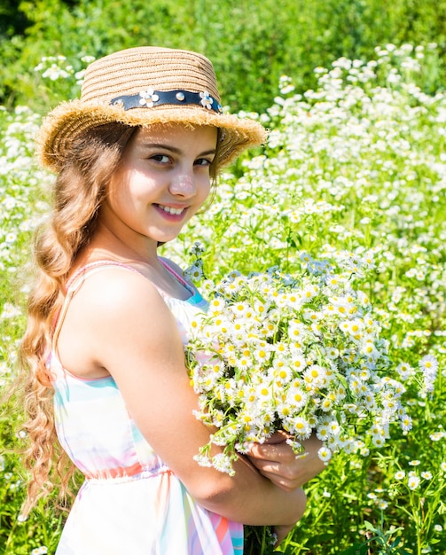 Raccogli erbe fresche Bambina che raccoglie fiori di camomilla nel concetto di flora di campo