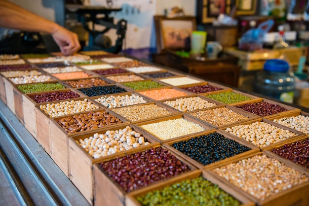 raccolta assortita di fagioli di semi colorati nella scatola di legno del negozio con prodotti selezionati per la mano degli uomini che mostrano il concetto di cibo salutare.