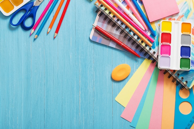 Raccolta dei rifornimenti di scuola sulla tavola di legno blu