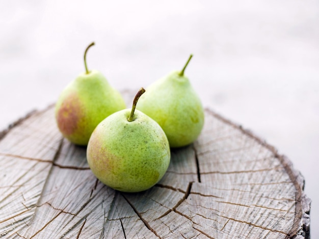 Raccolta. Una pera matura fresca della forma originale giace su un ceppo su uno sfondo naturale.