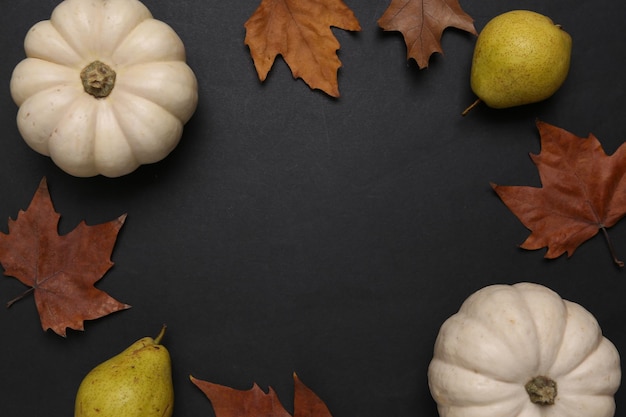 Raccolto autunnale Zucche pere e foglie cadute su sfondo nero Spazio di copia Vista dall'alto