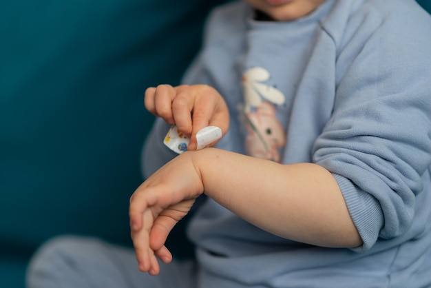 Raccolto di bambino bastone un cerotto sulla ferita sulle ginocchia Bambina bambino che indossa la colla blu con la toppa