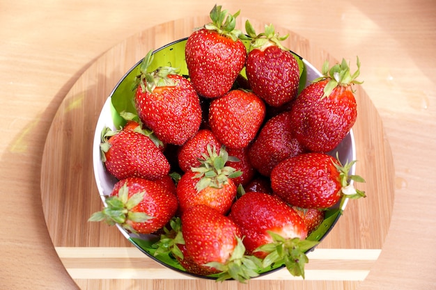 Raccolto fresco di fragola dal russo che dà in un'insalatiera trasparente