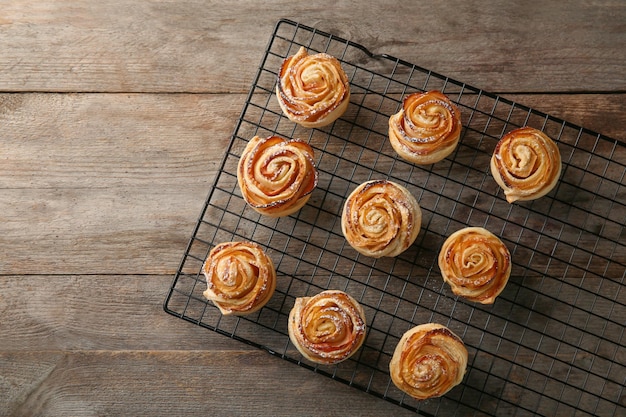 Rack di raffreddamento con rose di mele di pasta sfoglia su fondo di legno