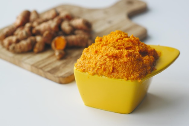 Radice di curcuma e incolla in una ciotola su sfondo bianco