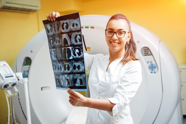 Radiologo femmina che esamina raggi x nella stanza della tomografia computerizzata.