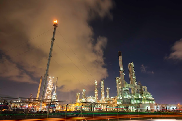 Raffineria di petrolio torre fuoco bagliore dell'industria petrolchimica in cielo nuvola sera
