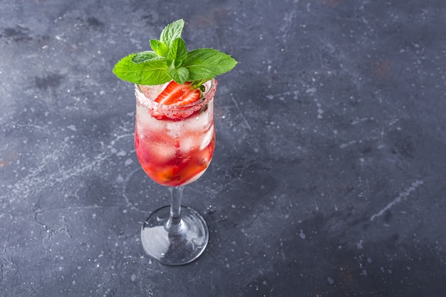 Raffreddamento cocktail alcolico italiano Rossini con spumante, fragola, cubetti di ghiaccio in bicchiere di champagne.