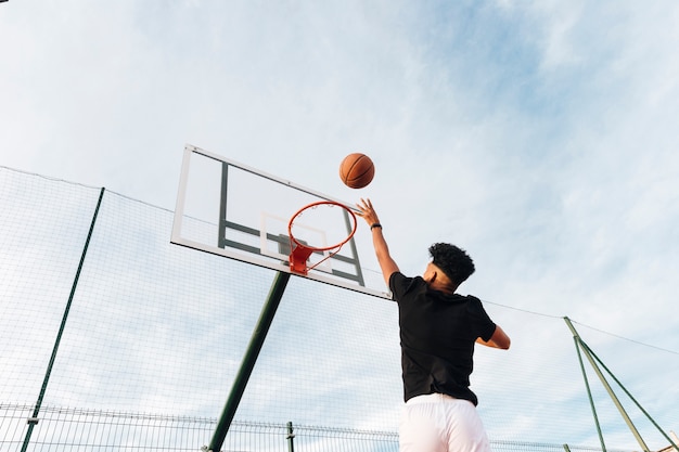 Raffreddi il giovane sportivo che getta la pallacanestro nel cerchio