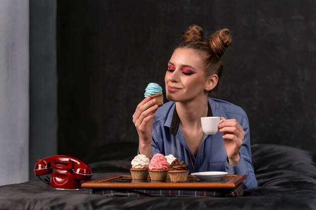 Ragazza a letto con cupcakes e tazza di caffè Lavoro freelance Lavoro a casa a letto Spazio di copia