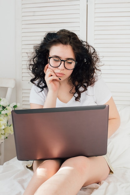 Ragazza a letto, lavorando su un computer portatile