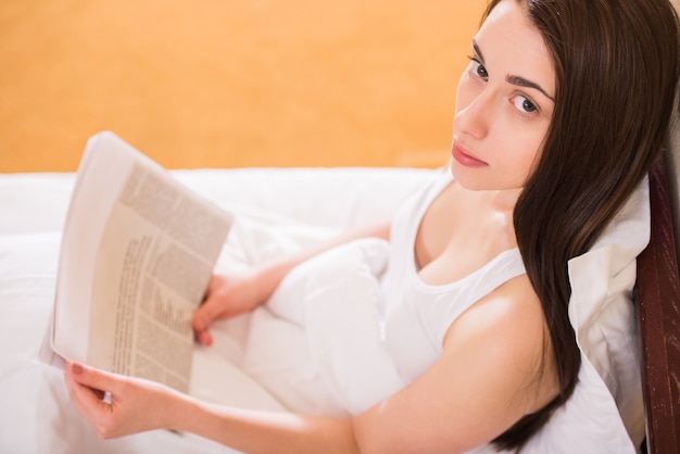 Ragazza a letto leggendo un giornale