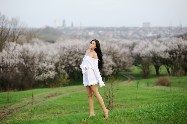 Ragazza a piedi nudi in abito bianco sull&#39;erba