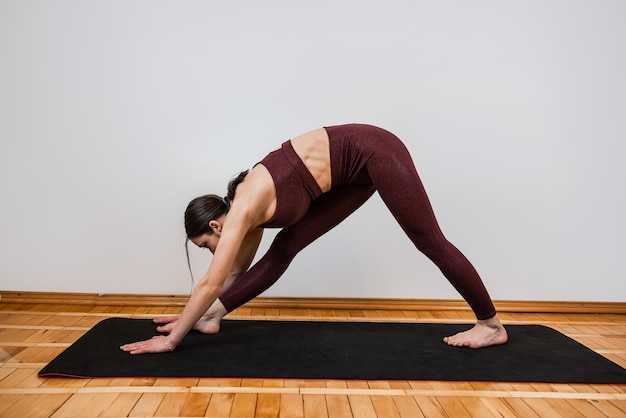 Ragazza abbastanza magra che fa stretching prima di esercizi più avanzati sul pavimento a casa stile di vita sano