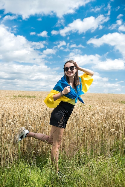 Ragazza abbastanza magra con bandiera giallo-blu dell'Ucraina nel campo di grano. stile di vita